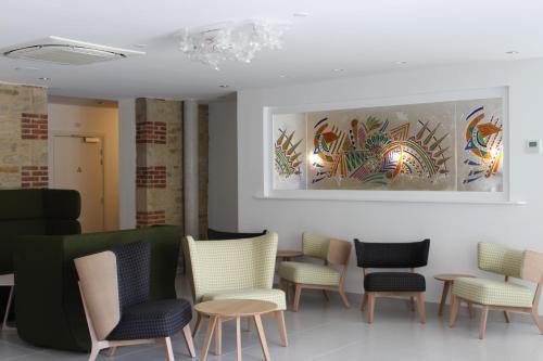 a waiting room with chairs and a painting on the wall at Hôtel Ginkgo - SPA Biloba in Quimper