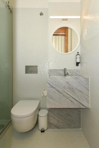 a bathroom with a toilet and a sink and a mirror at Republica 157 Guest House in Porto