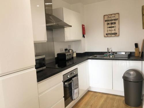 una cucina con armadi bianchi e piano cottura di City Centre Apartment a Portsmouth