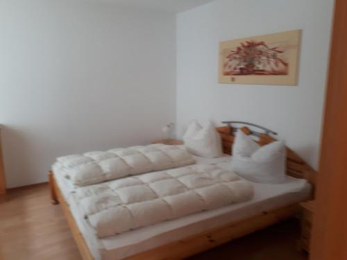 Un dormitorio con una cama blanca con almohadas. en Feriensiedlung Rother en Trassenheide