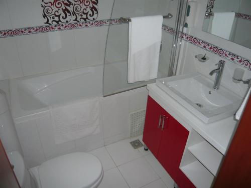 a white bathroom with a sink and a toilet at Le Relais de Bamako in Bamako