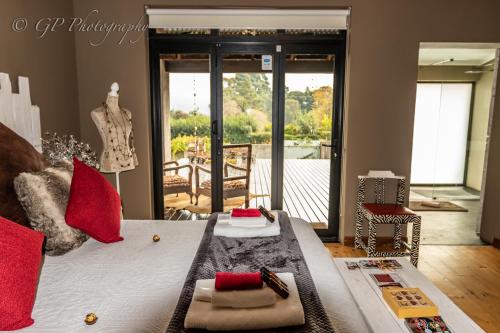 a bedroom with a bed with red pillows and a table at Laguna Lodge in Graskop