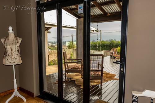 a glass door leading to a porch with a mannequin at Laguna Lodge in Graskop