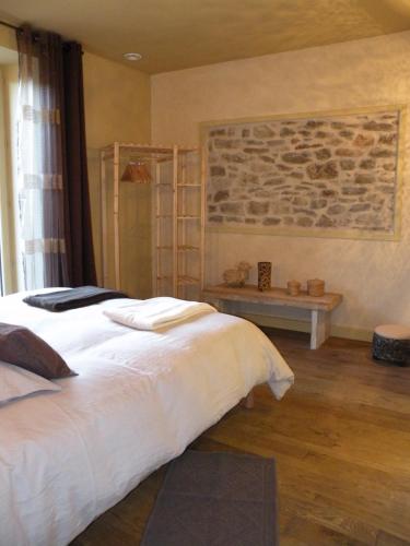 a bedroom with a white bed and a stone wall at Les Etoiles du Berger in Verrières
