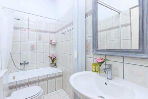 een badkamer met een wastafel, een toilet en een raam bij Agora Apartment in Limenas