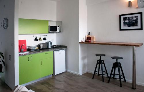 a kitchen with green cabinets and two bar stools at G38 Rental Apartment Building in Haifa