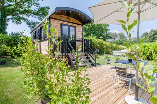 een tiny house op een terras met een tafel en een paraplu bij Roul'hôte du bout du monde in Landévennec
