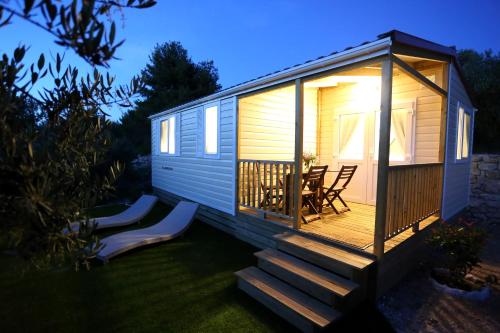 a tiny house with a deck and a table and chairs at Mobile homes-Slanica in Murter