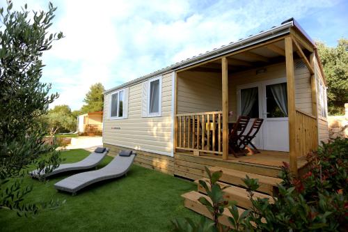 a tiny house with a deck and two chairs at Mobile homes-Slanica in Murter