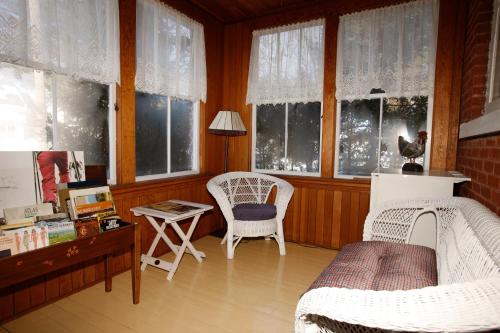 a living room with two chairs and a table and windows at Au Virage B&B in Magog-Orford