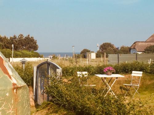 a garden with a table and chairs and a fence at Ual Öömrang Wiartshüs in Norddorf
