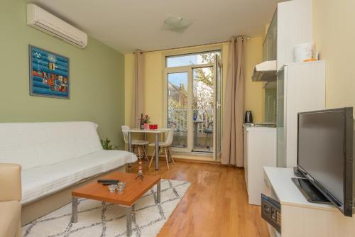 ein Wohnzimmer mit einem weißen Sofa und einem TV in der Unterkunft Studios Lulic in Makarska