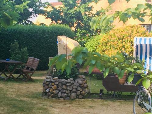 a garden with a bench and a stone wall at Ual Öömrang Wiartshüs in Norddorf