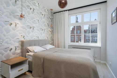 a white bedroom with a bed and a window at Elite Apartments Heart of the Old Town in Gdańsk
