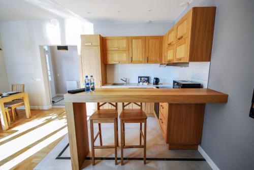 a kitchen with wooden cabinets and a counter with stools at Apartament Sokoła in Łańcut