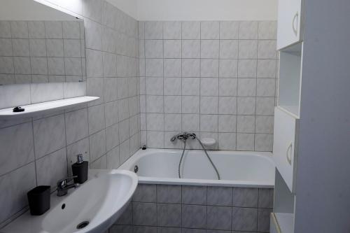 ein weißes Badezimmer mit einer Badewanne und einem Waschbecken in der Unterkunft Optimum Home in Pécs