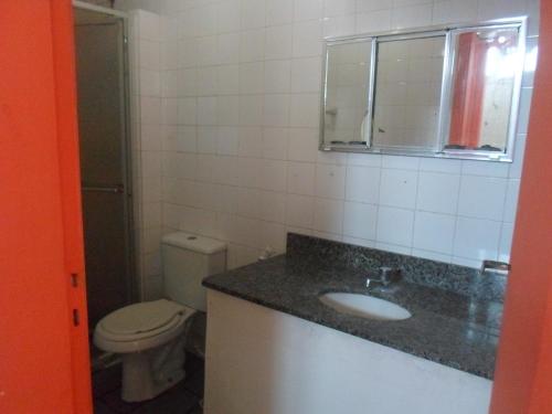 y baño con aseo, lavabo y espejo. en Apartamento no Porto da Barra, en Salvador