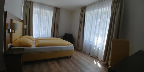 a bedroom with a bed and two large windows at ZUM ZIEL Hotel & Restaurant Grenzach-Wyhlen bei Basel in Grenzach-Wyhlen