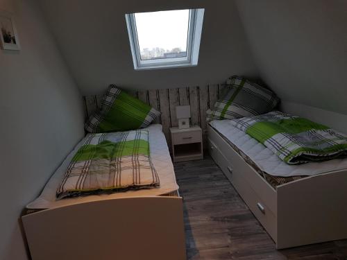 2 Einzelbetten in einem kleinen Zimmer mit Fenster in der Unterkunft Fehnhaus, Nordsee, Nähe Norddeich in Westermoordorf