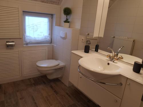 ein Badezimmer mit Waschbecken und Toilette und einem Fenster in der Unterkunft Fehnhaus, Nordsee, Nähe Norddeich in Westermoordorf