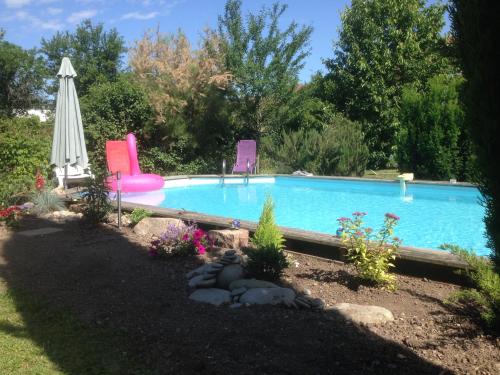 uma piscina com duas cadeiras e um guarda-sol em Gite des 3 cigognes em Colmar