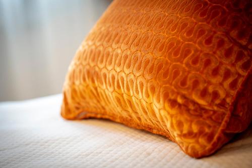 an orange pillow sitting on top of a bed at Casa Ercoli B&B in Vinci