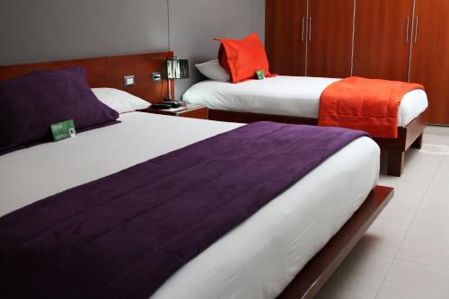 a hotel room with two beds with purple and orange sheets at Sunec Hotel in Chiclayo