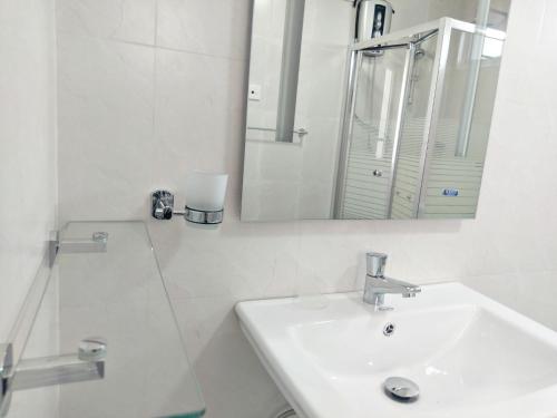 a white bathroom with a sink and a mirror at Mahaweli View Inn in Kandy