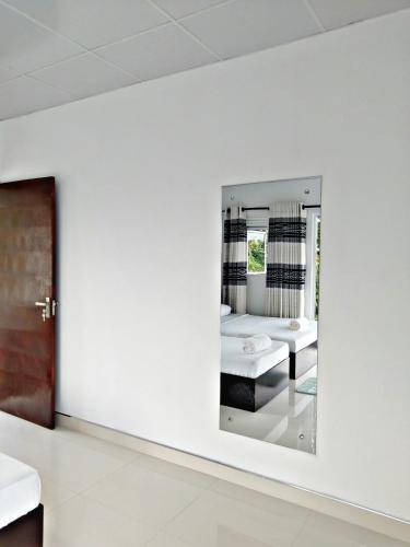 a mirror in a white room with a bed at Mahaweli View Inn in Kandy