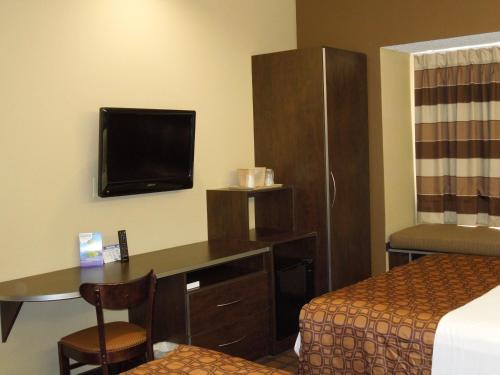 a hotel room with a bed and a desk and a tv at Microtel Inn & Suites by Wyndham Harrisonburg in Harrisonburg