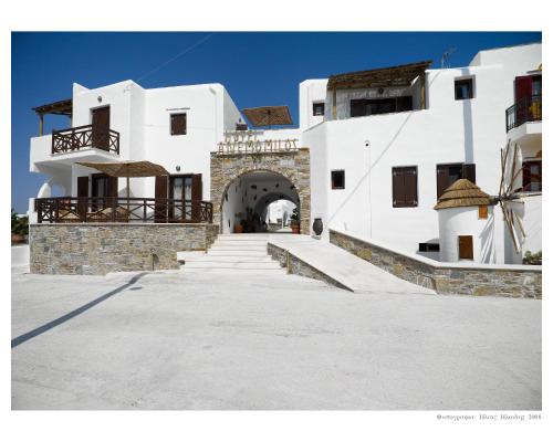 a large white building with an archway and stairs at Anemomilos Beach hotel in Agia Anna Naxos