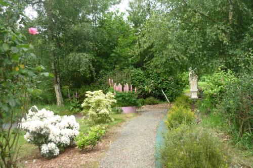 a path in a garden with flowers and trees at Gite Le Clos de Sée in Chérencé-le-Roussel