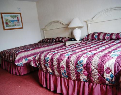 a hotel room with two beds and a lamp at Meadow Court Inn - Ithaca in Ithaca