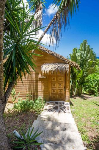 a small house with a wooden door in a yard at Carre Royal in Deshaies