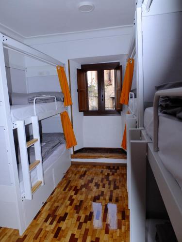 a small room with two bunk beds and a window at El Albergue de Sigüenza in Sigüenza
