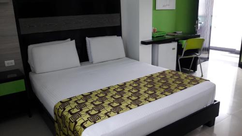 a bedroom with a large bed with a black and green headboard at Hotel Genova Prado in Barranquilla