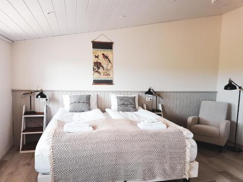 - une chambre avec un grand lit et une chaise dans l'établissement Grásteinn Guesthouse, à Þórshöfn