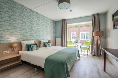 
a hotel room with a bed, chair, and nightstand at Duinhotel Zomerlust in Zoutelande
