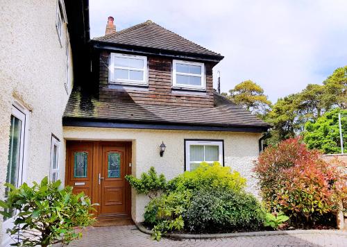 a white house with a brown door and windows at Wildwood B&B in Lymington