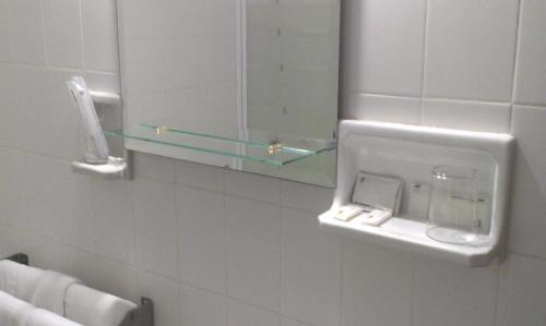 a bathroom with a mirror and a towel dispenser on the wall at Hotel Marina Victoria in Algeciras