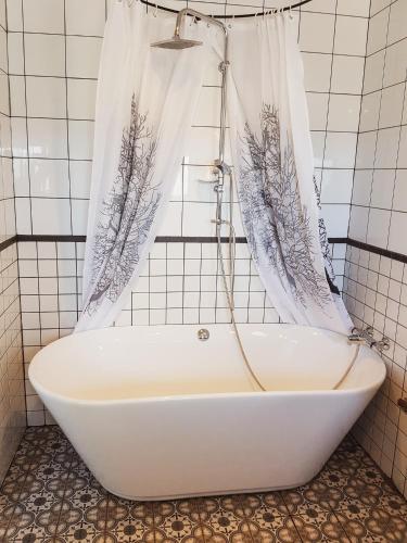 a bath tub in a bathroom with a shower curtain at Grásteinn Guesthouse in Þórshöfn