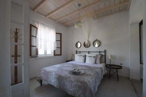 a white bedroom with a bed and a table at Maistros Holiday Home in Vourvourou