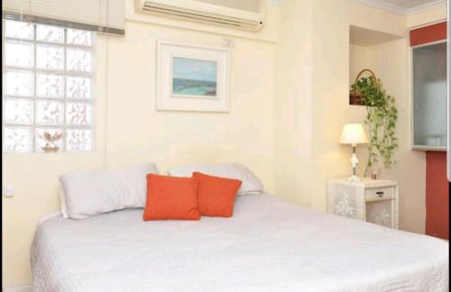 a bedroom with a white bed with two red pillows at Temporary Rental Apartments in Córdoba