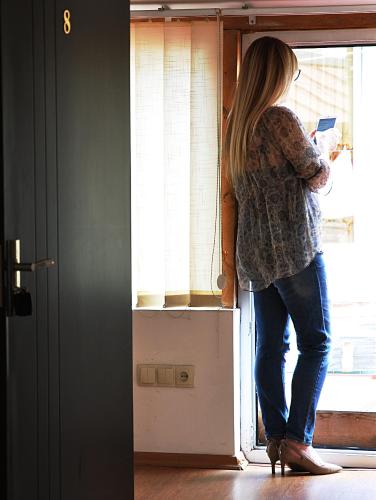 a woman standing at a window reading a book at Hotel Corner in Tbilisi City
