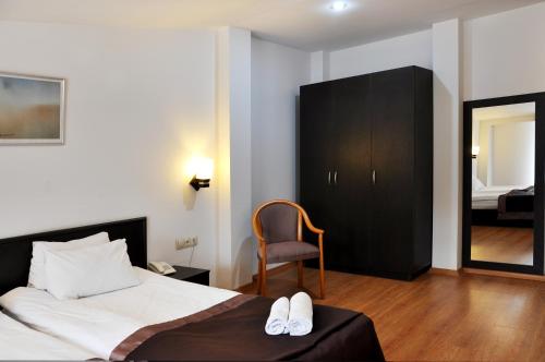 a bedroom with a bed and a chair and a mirror at Hotel Corner in Tbilisi City
