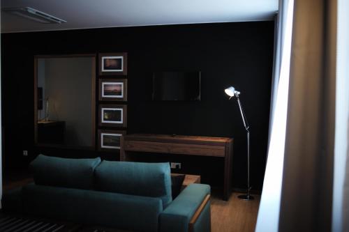a living room with a blue couch and a television at Hotel Cruzeiro in Angra do Heroísmo