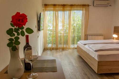Un dormitorio con una cama y una mesa con un jarrón con una rosa en Apartmani Mendula, en Budva