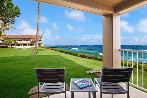 two chairs and a table on a porch overlooking the ocean at The ISO in Kapaa