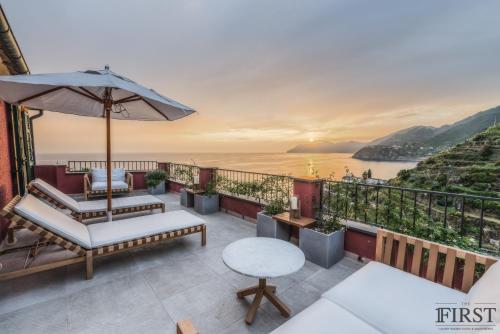 a balcony with a table and an umbrella and the ocean at Il Sogno di Manarola by The First in Manarola