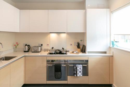a kitchen with white cabinets and an oven at Trumpington Townhouse with Parking and sleeps 6 - Addenbrookes hospital- 5 mins in Cambridge
